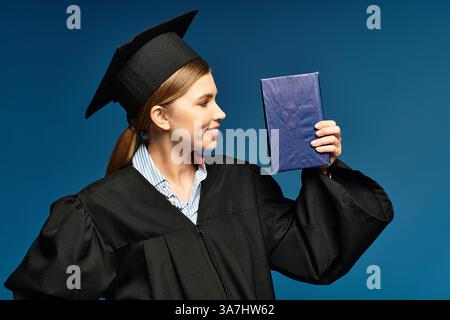 Une jeune femme heureuse dans une robe de graduation montre fièrement son diplôme. Banque D'Images