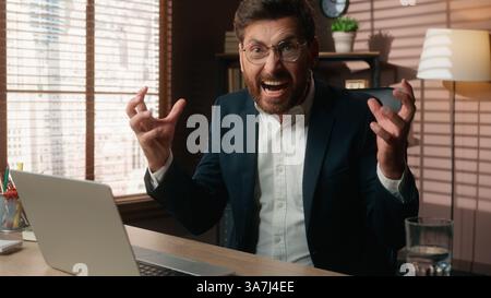 Stressé homme d'affaires caucasien surmenagé burnout agressif homme en colère agacé homme d'affaires agacé hurlant dactylographiant ordinateur portable Banque D'Images