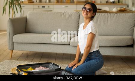 Femme indienne femme arabe fille féminine à la maison se préparant à voyage vacances voyage pack vêtements dans la valise bagage bagage emballage tissu été Banque D'Images