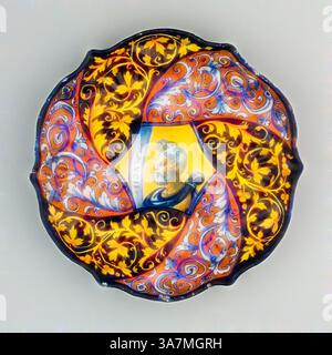 Assiette décorative aux motifs complexes et tourbillonnants aux couleurs vives, représentant un portrait central d'une figure distinguée entourée de motifs floraux ornés. La combinaison d'éléments artistiques crée une pièce maîtresse saisissante et visuellement captivante., Art classique avec une touche moderne réinventée par Artotop, bol avec un buste de Mucius Scaevola, 1535/45, Italien, Faenza, Faenza, faïence émaillée en étain (maiolica), diamètre : 25,4 cm (10 po.) Banque D'Images