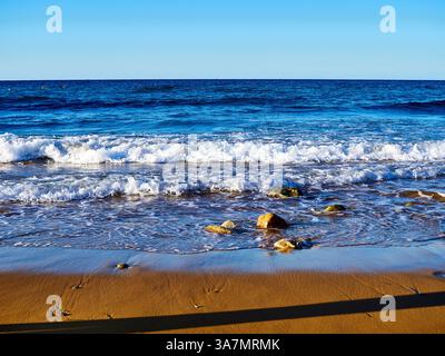 Beau paysage marin avec des vagues, des rochers et un ciel bleu sur la plage de Ramla, Malte Banque D'Images