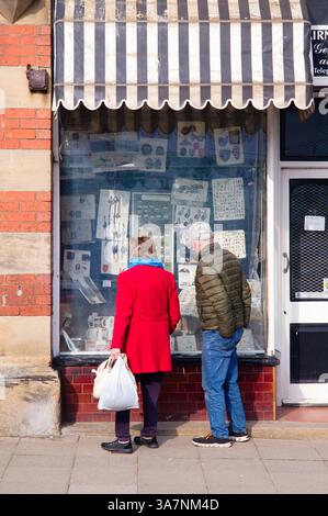 Un couple plus âgé regardant dans la fenêtre de Cairncross et les fils boutique à Filey Banque D'Images