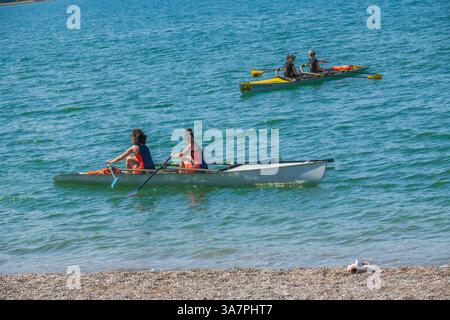 Deux équipes d'aviron pratiquent près du rivage par une journée ensoleillée, mettant en valeur le travail d'équipe, la force et la coordination dans le sport de l'aviron. Banque D'Images