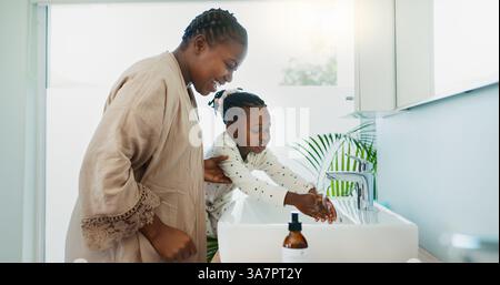 Hygiène, aide et mère noire avec enfant pour se laver les mains dans la salle de bain pour apprendre. Maman heureuse, enseignante et africaine avec fille pour nettoyer la peau Banque D'Images