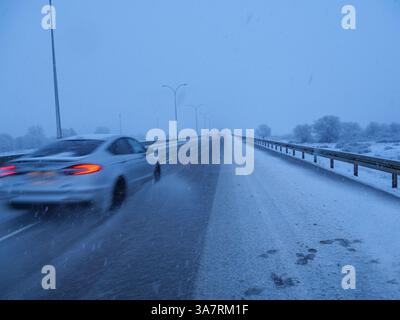 Vehicles struggle to navigate a snow-covered highway during a winter storm. Banque D'Images
