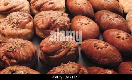 Pains sur l'étagère dans le marché ou la boulangerie. variété de pâtisseries avec différentes formes et garnitures. les pâtisseries sont disposées dans une rangée, avec certaines étant l Banque D'Images