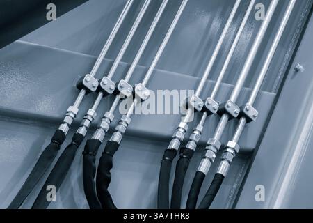Une rangée de tuyaux métalliques de l'entraînement d'une machine pneumatique hydraulique industrielle, les tuyaux sont reliés les uns aux autres. Les flexibles en caoutchouc noir sont branchés Banque D'Images