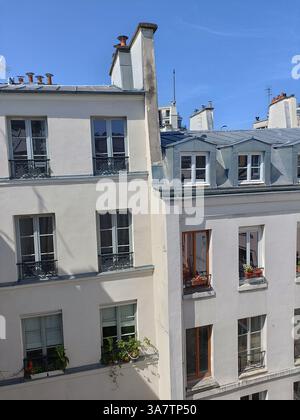 Toits parisiens typiques avec lucarnes et immeubles résidentiels de style haussmannien sous ciel bleu, Paris France Banque D'Images