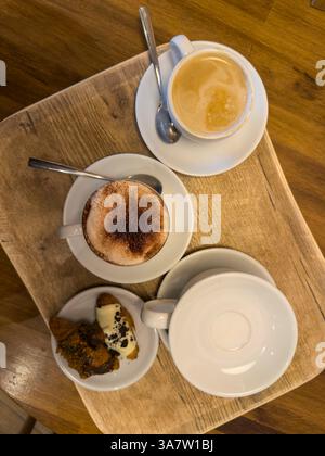 Cappuccino, café et mini-croissants servis sur un plateau en bois, créant une scène de petit-déjeuner confortable Banque D'Images