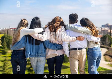 Groupe d'étudiants divers se serrant les uns les autres, appréciant la camaraderie et regardant le paysage urbain Banque D'Images