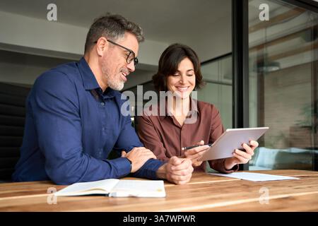 Deux collègues d'affaires heureux ayant la conversation lors de la réunion de bureau en utilisant TAB. Banque D'Images