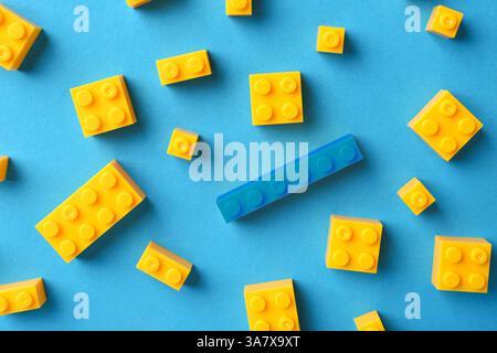 Différence, unicité, individualité. Bloc de construction bleu parmi les jaunes sur fond de couleur, vue de dessus Banque D'Images