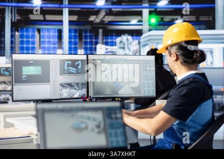 Spécialiste de l'usine photovoltaïque utilisant PC pour effectuer des tests de performance des conceptions de panneaux solaires. Employé regardant le moniteur d'ordinateur, l'amélioration des configurations de panneaux solaires existantes pour la réduction des coûts en utilisant Banque D'Images