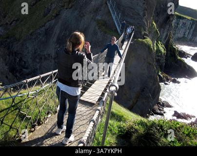 19 août 2011 - Causeway Coast, Irlande du Nord, Royaume-Uni - Un touriste pose pour une photographie sur le pont de corde Carrick-a-Rede, un célèbre pont de corde près de Ballintoy dans le comté d'Antrim sur la côte de Causeway en Irlande du Nord. Le pont relie le continent à la petite île de Carrickarede. Il s'étend sur 20 mètres et se trouve à 30 mètres au-dessus des rochers en contrebas. (Crédit image : © Deirdre Hamill/ZUMAPRESS.com) Banque D'Images