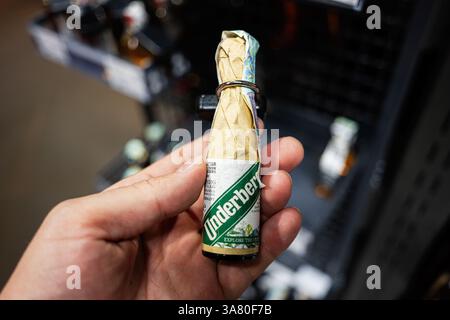 Lviv, Ukraine - 25 mars 2025 : un gros plan d'une bouteille amère à base de plantes Underberg tenue par une main en magasin. Banque D'Images