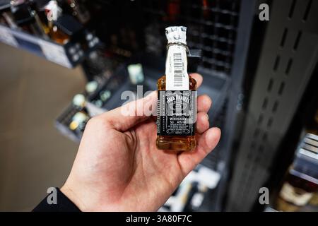 Lviv, Ukraine - 25 mars 2025 : main tenant une mini bouteille de whisky Jack Daniel dans une zone d'exposition de magasin. Banque D'Images