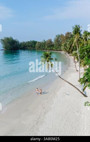 Le sable étincelant s'étend le long de la côte tranquille de l'île de Koh Kood en Thaïlande, où les visiteurs se promènent sous les palmiers oscillants. Un paradis parfait pour la détente et l'exploration. Banque D'Images
