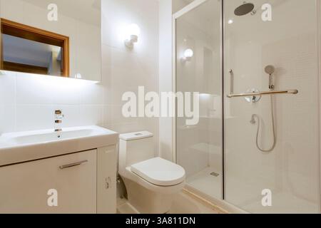 Salle de bains moderne avec douche en verre et luminaires dorés Banque D'Images