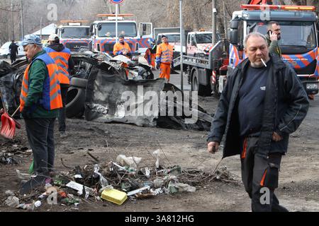Des travailleurs de l’entreprise municipale “infrastructure de transport de la ville” évacuent des voitures détruites par une attaque de drone russe, Dnipro, Ukraine, le 27 mars 2025 (photo de Dmytro Smolienko/Ukrinform) Banque D'Images