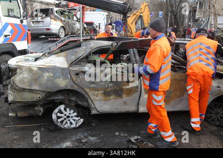 Des travailleurs de l’entreprise municipale “infrastructure de transport de la ville” évacuent des voitures détruites par une attaque de drone russe, Dnipro, Ukraine, le 27 mars 2025 (photo de Dmytro Smolienko/Ukrinform) Banque D'Images