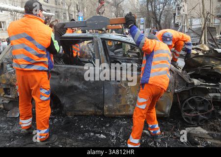 Des travailleurs de l’entreprise municipale “infrastructure de transport de la ville” évacuent des voitures détruites par une attaque de drone russe, Dnipro, Ukraine, le 27 mars 2025 (photo de Dmytro Smolienko/Ukrinform) Banque D'Images
