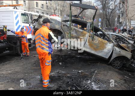 Des travailleurs de l’entreprise municipale “infrastructure de transport de la ville” évacuent des voitures détruites par une attaque de drone russe, Dnipro, Ukraine, le 27 mars 2025 (photo de Dmytro Smolienko/Ukrinform) Banque D'Images