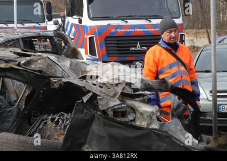 Des travailleurs de l’entreprise municipale “infrastructure de transport de la ville” évacuent des voitures détruites par une attaque de drone russe, Dnipro, Ukraine, le 27 mars 2025 (photo de Dmytro Smolienko/Ukrinform) Banque D'Images