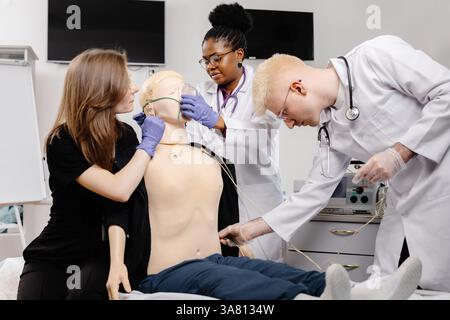 Groupe diversifié d'étudiants en médecine pratiquant l'intubation endotrachéale lors d'une formation de simulation en soins d'urgence avec un mannequin médical Banque D'Images