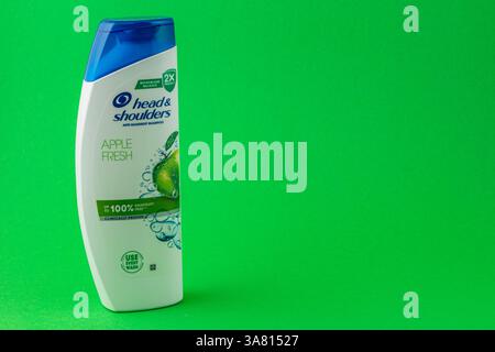 24.03.25 Lviv Ukraine Une bouteille de shampooing antipelliculaire se tient debout sur un fond vert vif. La conception met en évidence un thème pomme, soulignant Banque D'Images