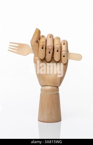 Fourchette jetable en bois dans une main en bois d'un mannequin sur un fond blanc. Concept de nourriture saine et concept de produits naturels Banque D'Images
