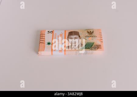 Un paquet de billets de banque en roupie indonésienne, soigneusement empilés sur une surface propre et lumineuse. Montre le concept de finance, d'économie et de monnaie indonésienne. Banque D'Images