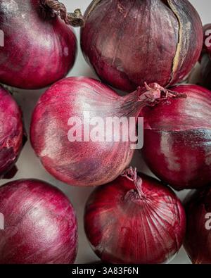 Gros plan d'oignons rouges non pelés avec leur peau de papeterie rouge foncé Banque D'Images