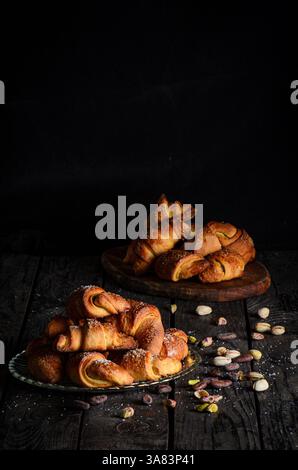 Un ensemble de petits pains doux, brun doré fourrés de chocolat riche et de pistache crémeuse, servis élégamment sur des assiettes en verre. Banque D'Images