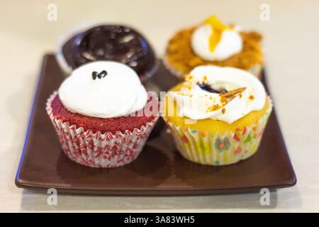 Quatre différents types de cupcakes, chacun avec une garniture de glaçage unique, servis dans un café local à Mindanao, Philippines Banque D'Images