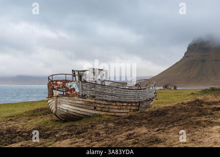 Un bateau abandonné et en décomposition repose sur la terre près de Kirkjufell en Islande Banque D'Images