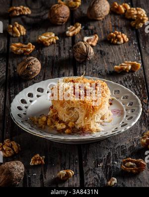 Dessert Kadaif, une pâtisserie sucrée traditionnelle du moyen-Orient et de la Méditerranée, servie sur une surface en bois foncé. Banque D'Images