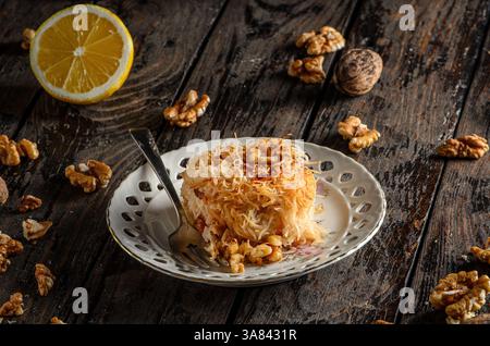 Dessert Kadaif, une pâtisserie sucrée traditionnelle du moyen-Orient et de la Méditerranée, servie sur une surface en bois foncé. Banque D'Images