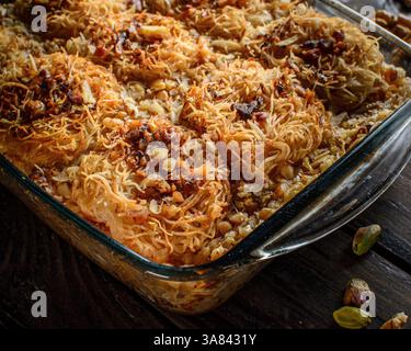 Dessert Kadaif, une pâtisserie sucrée traditionnelle du moyen-Orient et de la Méditerranée, servie sur une surface en bois foncé. Banque D'Images