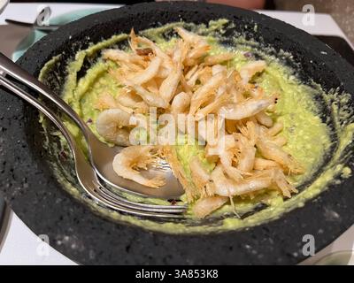 Guacamole crémeux garni de crevettes frites croustillantes, servies dans un bol en pierre traditionnel, prêt à être dégusté Banque D'Images