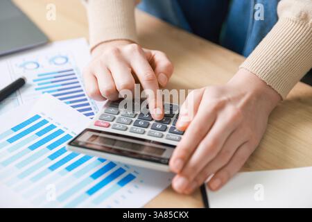 Budget. Femme avec la paperasse et la calculatrice au bureau en bois à l'intérieur, gros plan Banque D'Images