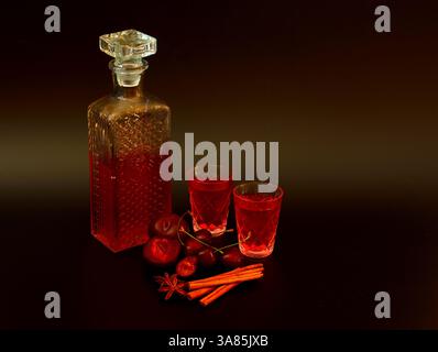 Liqueur de prunes-cerises à la cannelle et à l'anis sur fond noir dans une carafe en cristal et deux verres. Gros plan. Banque D'Images