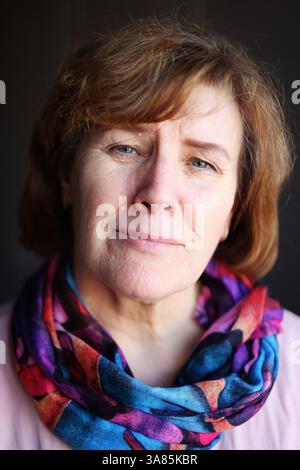 Femme âgée heureuse avec les cheveux courts et l'écharpe brillante, regardant la caméra avec le sourire chaud. Banque D'Images