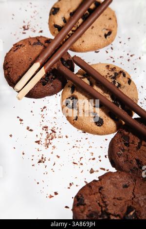 biscuits avec des morceaux de chocolat et bâtonnets de chocolat sur fond blanc Banque D'Images