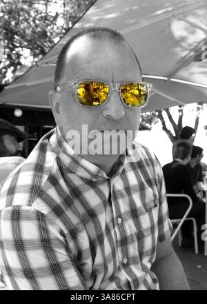 photo en noir et blanc d'un homme d'âge moyen frais dans une chemise à carreaux portant des lunettes de soleil réfléchissantes orange - couleur tache Banque D'Images