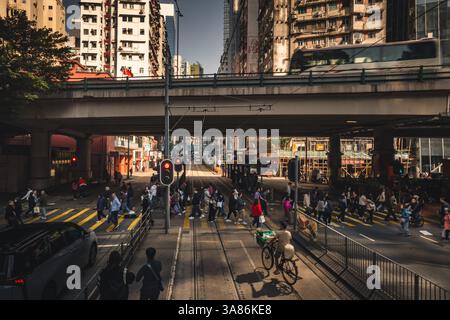 Une scène de rue avec un tramway de Hong Kong en arrière-plan avec des piétons traversant une rue animée, Hong Kong, Chine Banque D'Images