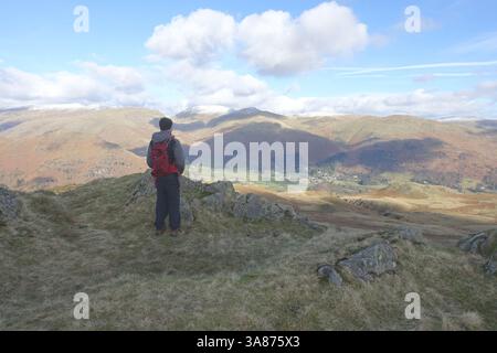 Homme (randonneur) debout sur le Birkett 'Lang How' Crag regardant vers le bas sur la vallée de Grasmere dans le parc national du Lake District, Cumbria, Angleterre, Royaume-Uni Banque D'Images