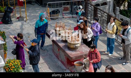 Hong Kong. Chine- 02.24.2025. Vue en grand angle des pèlerins offrant des biens religieux, brûlant de l'encens et priant aux divinités à Sik Sik Yuen Wong Tai si Banque D'Images