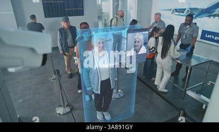 Point de contrôle de l'aéroport : file d'attente de diverses personnes passant le balayage biométrique des visages IA au contrôle des frontières. Caméra de sécurité avec technologie avancée de reconnaissance faciale. Filtrage des passagers pour l'embarquement sur le vol. Banque D'Images