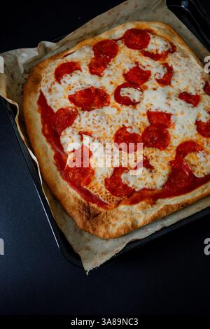 Pizza gourmande pepperoni de style dark food, mettant en valeur ses ingrédients dans un cadre sophistiqué. Banque D'Images
