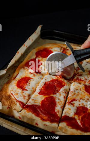 Pizza gourmande pepperoni de style dark food, mettant en valeur ses ingrédients dans un cadre sophistiqué. Banque D'Images